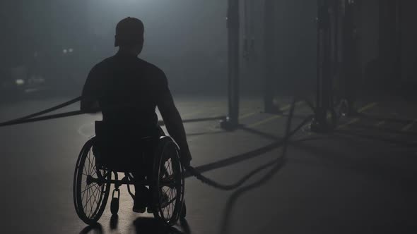 Workout Disabled Man in Wheelchair Performs Exercises with Battle Ropes Crossfit Endurance Training