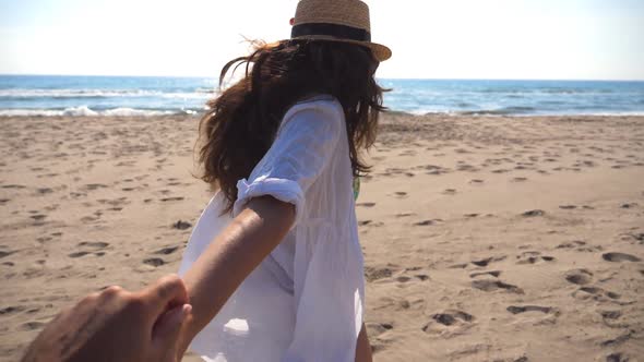 Girl Holding Male Hand and Running on Beach to the Ocean