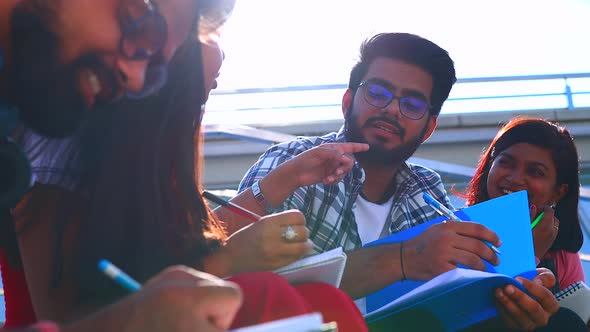 Indian Friends Sitting on Stairs Outdoors with Copybooks