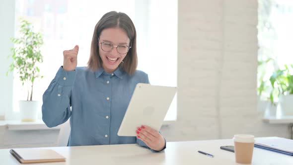 Young Woman Celebrating Online Success on Tablet