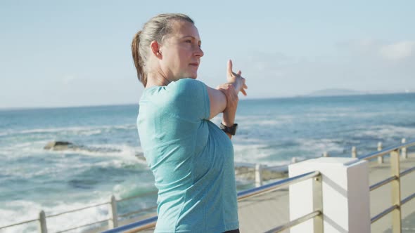 Senior woman stretching her arms on a promenade