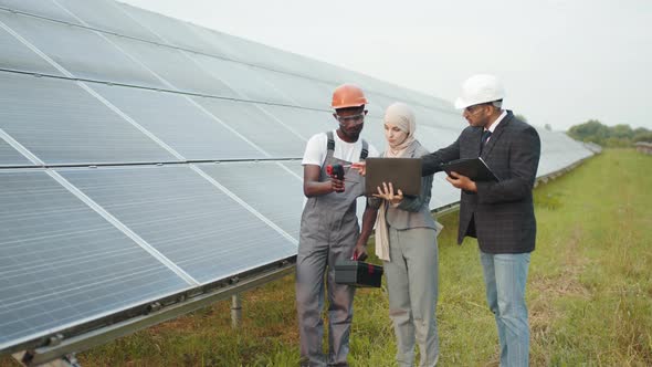 African Technician Measuring Temperature of Solar Panels with Thermal Imager