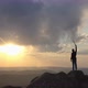 Drone Shot of a Silhouette of a Mountaineer Standing on Top of a Mountain and Victoriously Raising - VideoHive Item for Sale
