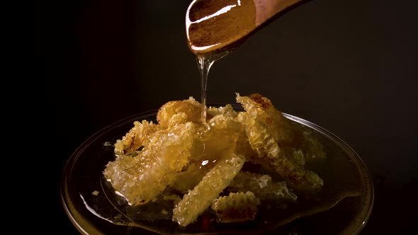 Honey Flows From a Wooden Spoon on a Honeycomb