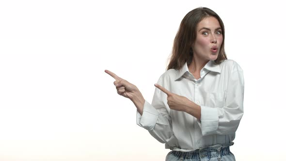 Beautiful Woman in White Shirt Pointing Fingers Left at Blank Space for your Logo Showing Product