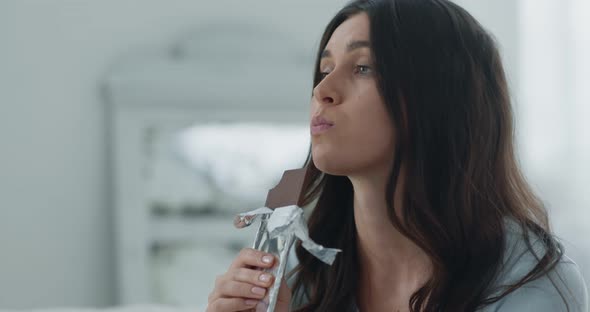 Seizing Stress. Close Up Portrait of Young Depressed Woman Eating Chocolate Bar Slow Motion