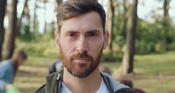 Man which Posing on Camera on the Background of Group of People which Rubbish into Plastic Bags