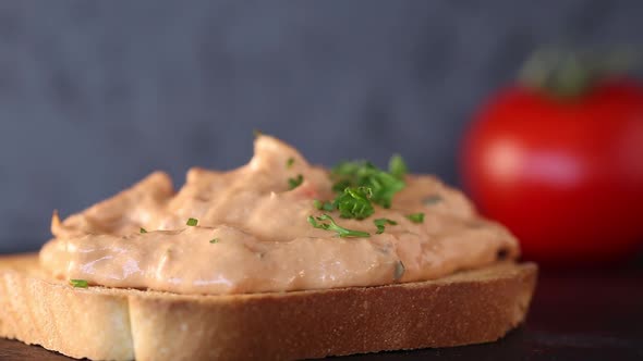 Spreading chopped parsley over tuna paste on toast