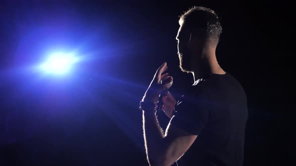 Young Male Business Coach Speaking Through a Microphone in a Dark Conference Room