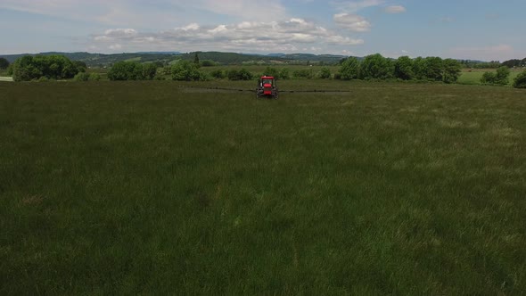 Aerial shot of tractor spraying grass seed farm