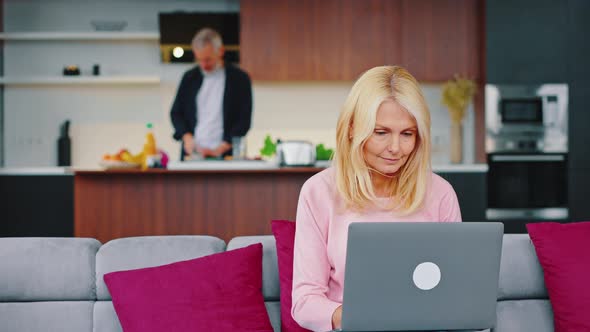 Selective Focus of Serious Adult Female Freelancer Working on Laptop in Kitchen Studio Near Her