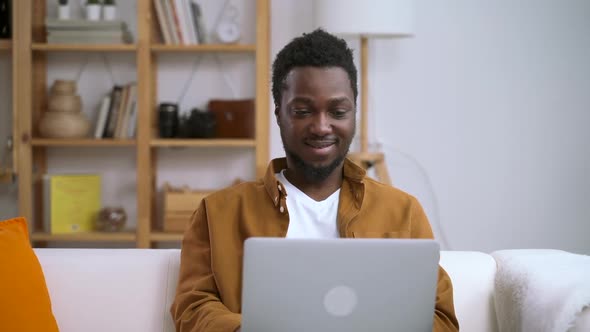 African Man Working at Home on Computer on Background of Interior Spbas