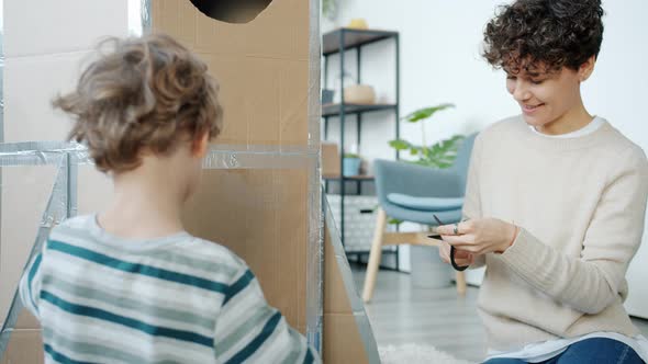 Portrait of Creative People Mother and Son Decorating Handmade Spaceship Playing at Home