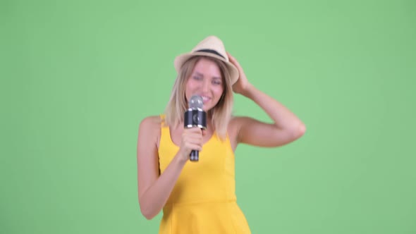 Happy Young Blonde Tourist Woman Singing with Microphone