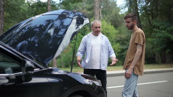 Worried Young Man Arguing with Angry Middle Aged Guy Shouting and Gesturing