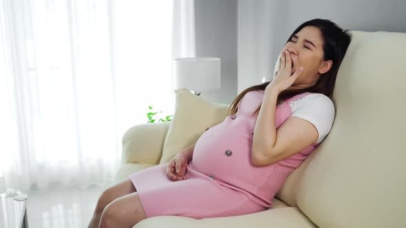 pregnant woman yawning and sleeping on sofa in the living room