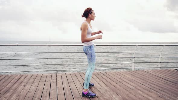 Athletic Young Woman Doing Backbend and Stretching on the Beach By the Ocean