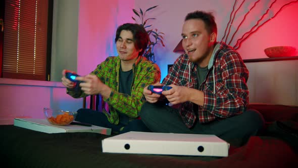 Two Young Men Sitting on the Bed and Playing Game