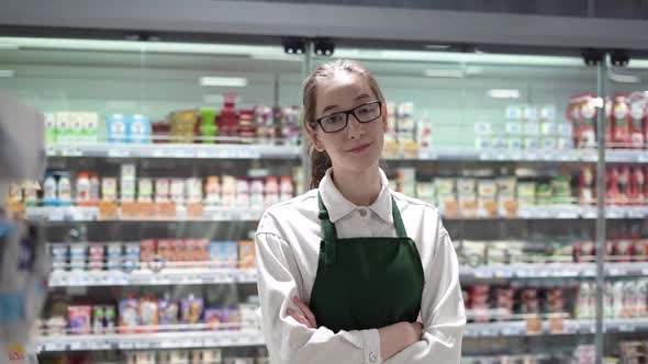 A Supermarket Salesgirl Smiling Into the Camera