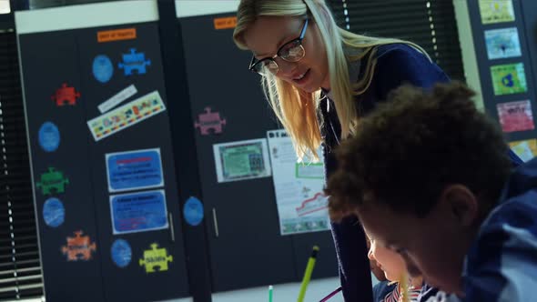 Teacher helping schoolkids with their homework in classroom