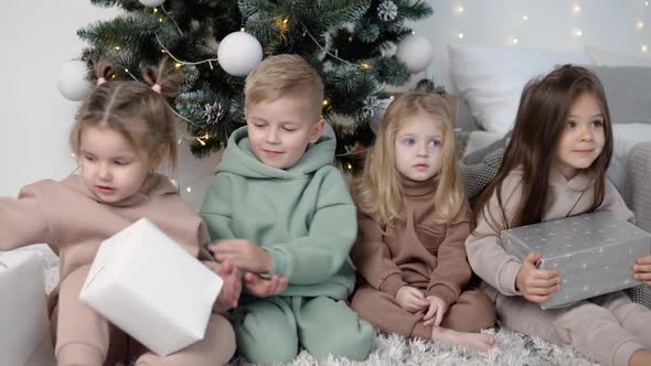 Children Sitting Near Christmas Tree and Share Their Presents