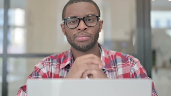 Close Up of African Man with Laptop Looking in Camera