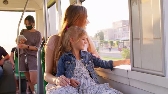 Family Rides in Public Transport Mother with Little Daughter Sit Together and Look Out Window Tram