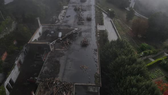 Aerial top-down forward over roof of Caramulo Sanatorium abandoned building on foggy day. Portugal