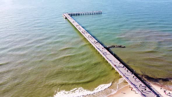 People enjoy sunny day on Palanga bridge, aerial descend view