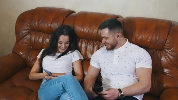 Happy couple sitting in a comfortable couch in the hotel room and resting after road.