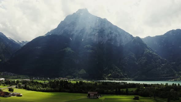 Alpine Mountains in the Sunlight at Foot of Which There is a Village and a Lake