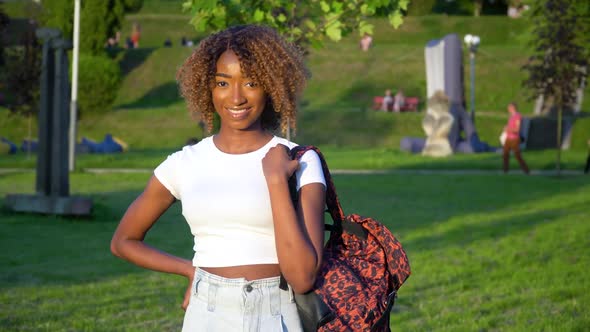 Smiling Young African American Female Student in University Park with a Backpack