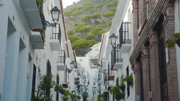 Narrow street in spanish town of Mijas below mountain, tilt shot.