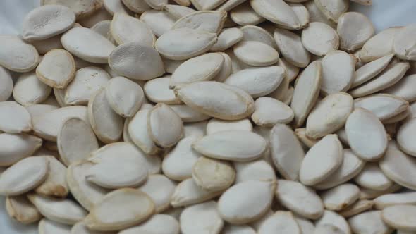 Close-up of a bunch of white pumpkin seeds rotating. Falling pumpkin seeds