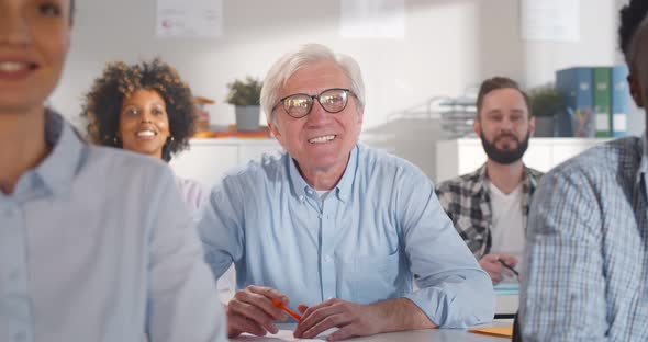 Diverse Adult Students in Classroom with Papers Studying at Courses