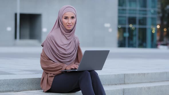Beautiful Muslim Girl in Hijab Scarf Islamic Woman Using Wireless Laptop Working Outdoors Looking at