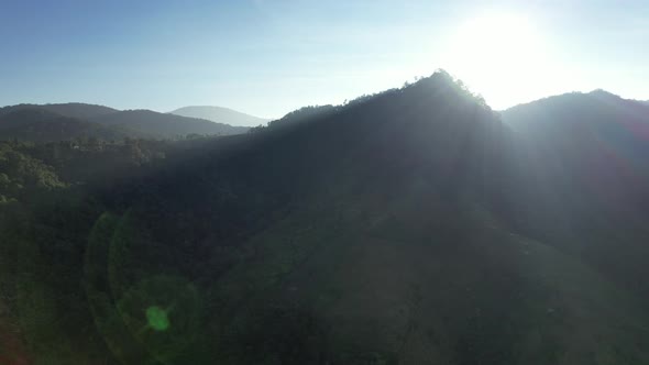 Aerial landscape view of the sun is shining through the greenery rainforest mountains by drone