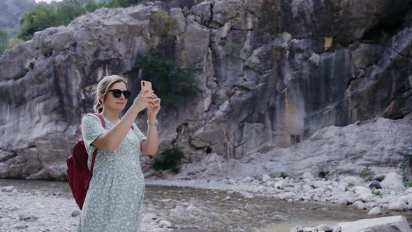 Pregnant Girl Stands Near a Mountain River and Takes Pictures on the Phone