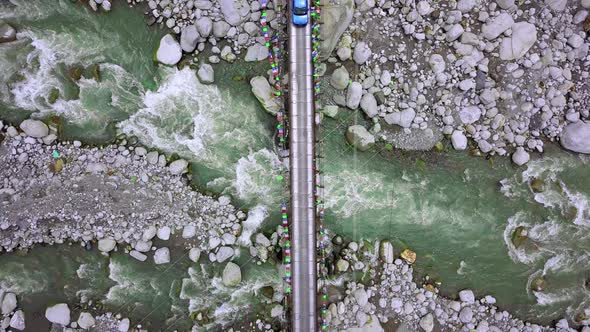 A Beautiful Aerial Looking Down Shot of Bright Blue Car Crossing a Suspension Bridge 