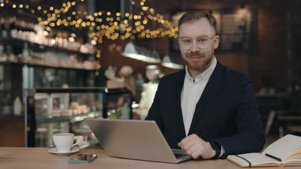 Portrait of Businessman Looking at Camera While Working in Cafeteria