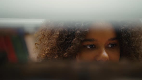 Young Black Female Searching for Book on Shelves alt