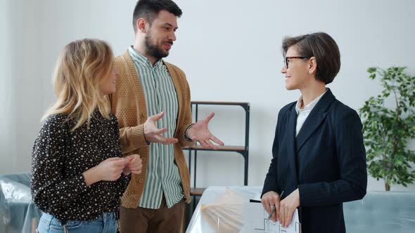 Couple of Buyers Talking To Real Estate Agent Discussing Sales Deal in Modern House