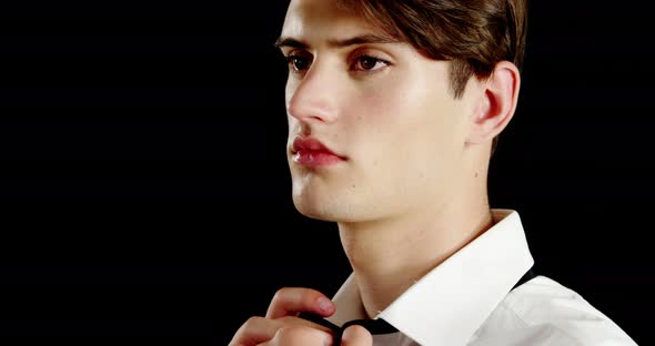Androgynous man adjusting bow tie