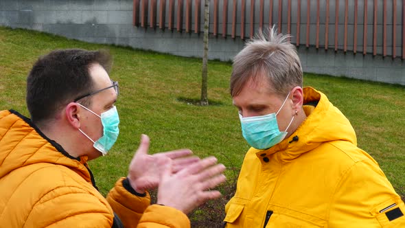 Couple of Men in Medical Masks Have a Conversation