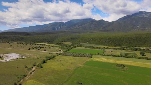 Drone Flying Over Fileds With Mountains And Clouds On The Horizon