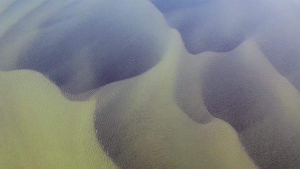 Aerial top down shot of Olfusa River with dark pattern underwater during sunny day on iceland