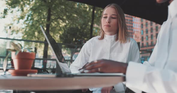 Two women talk business while one types on laptop