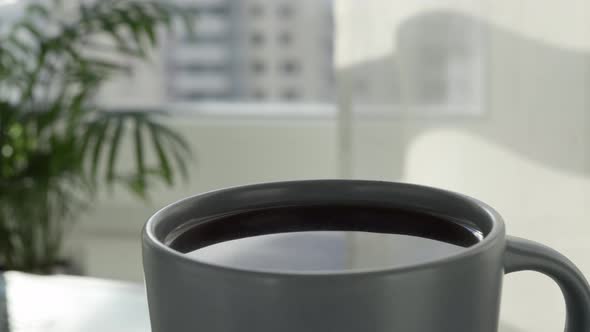A close-up view of cup of hot coffee from which natural steam rises