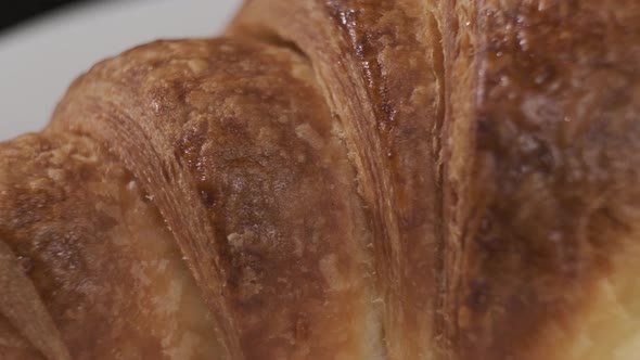 Croissant on white plate rotating in front of camera on black background