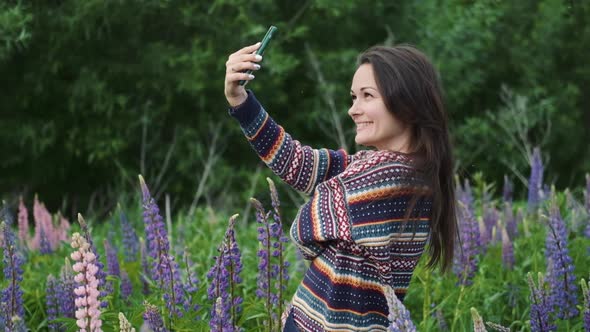 Happy Woman Enjoying the Outdoors Using Her Cell Phone, young Brunette Takes a Selfie on a Background